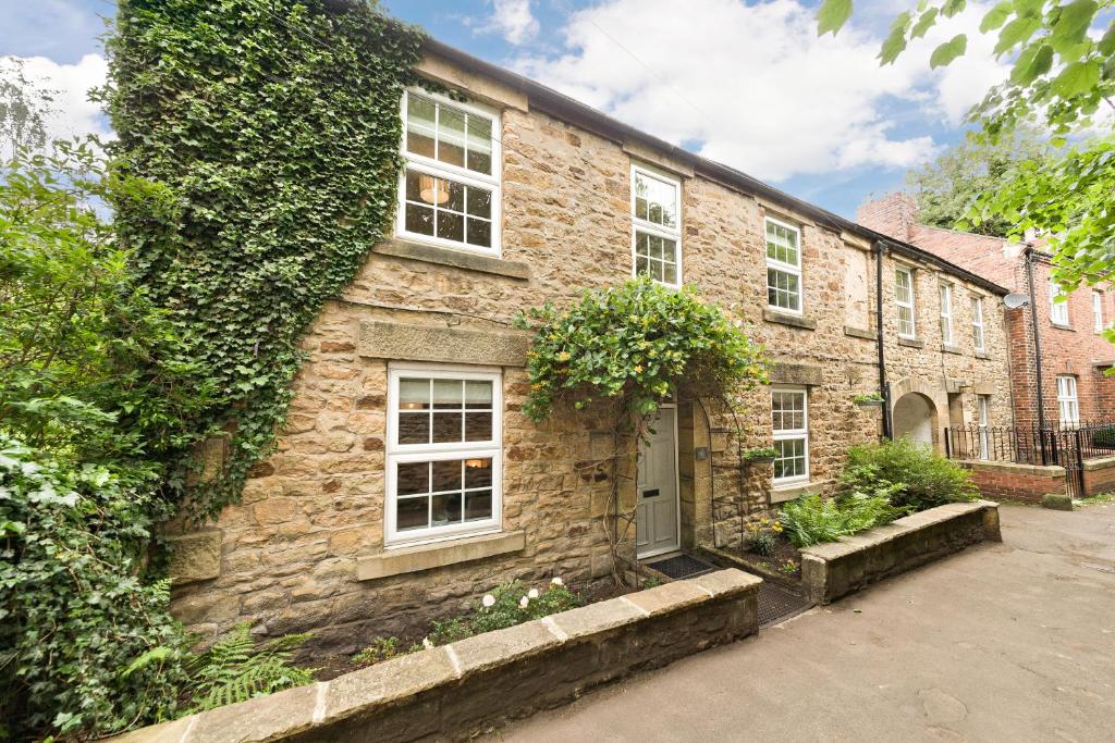 un edificio de ladrillo con ventanas y hiedra en él en Seal Cottage, en Hexham