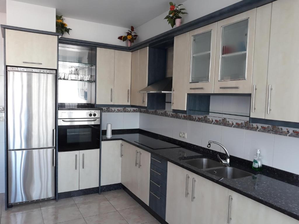 a kitchen with white cabinets and black counter tops at O'Corpiño in Muxia