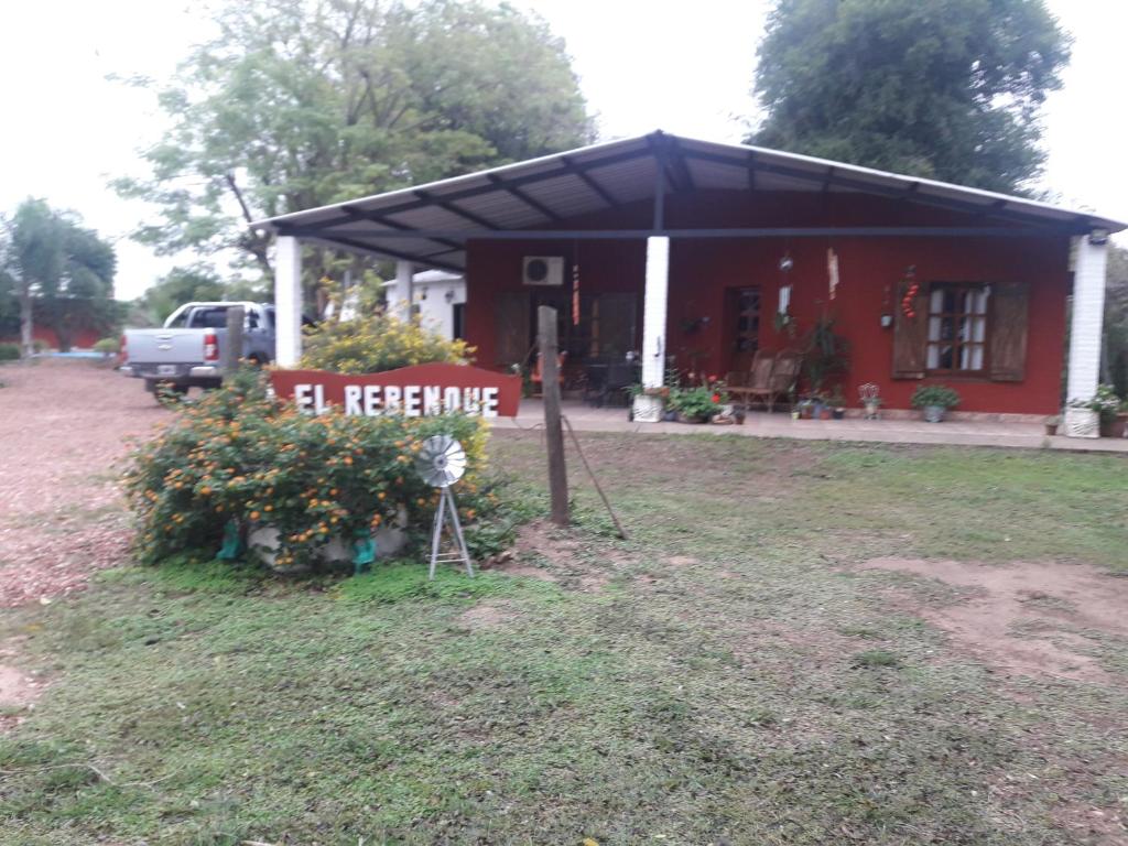 een rood huis met een bord ervoor bij Hotel de Campo El Rebenque in Aviá Terai