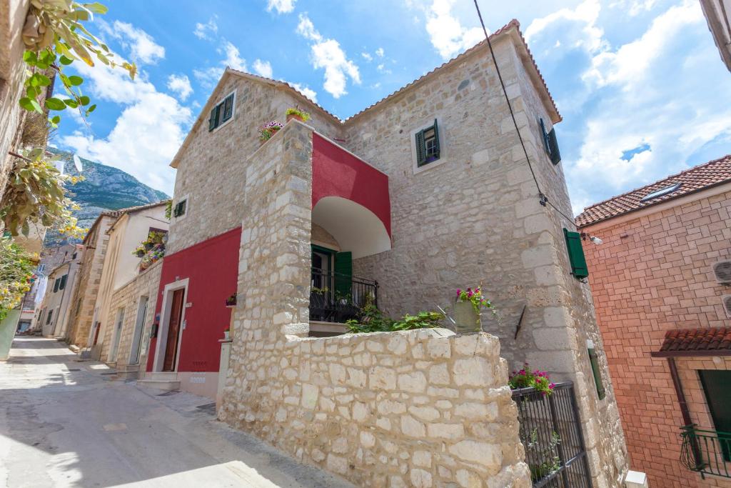 a stone building with a red door on a street at Apartments Linda in Makarska