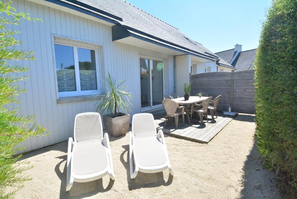 eine Terrasse mit weißen Stühlen und einem Tisch und einem Zaun in der Unterkunft Roches Blanches 3 in Saint-Lunaire