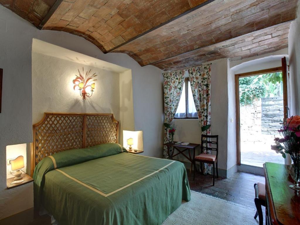 sypialnia z zielonym łóżkiem i dużym oknem w obiekcie Villa Le Barone w mieście Panzano in Chianti
