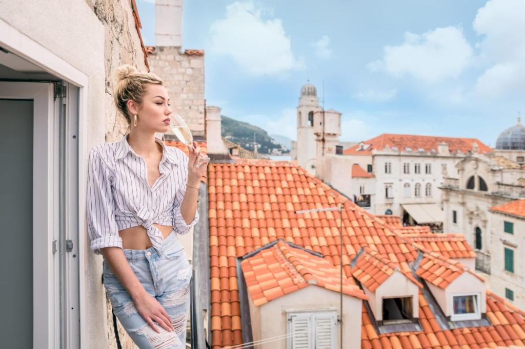 Eine Frau steht auf einem Balkon mit Blick aus dem Fenster in der Unterkunft Scalini Palace in Dubrovnik