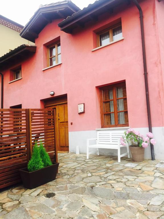 a pink house with a bench in front of it at La Quintana de Somao, Casa de Arriba in Somado