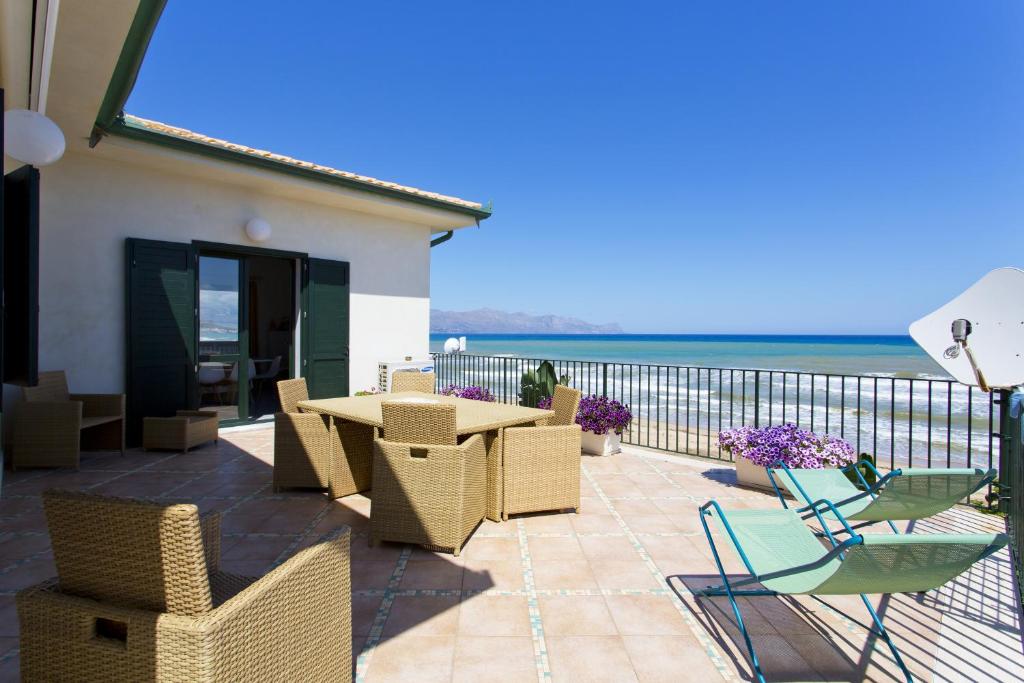 un patio con mesa, sillas y el océano en Dune Home alloggi sul mare, en Alcamo Marina