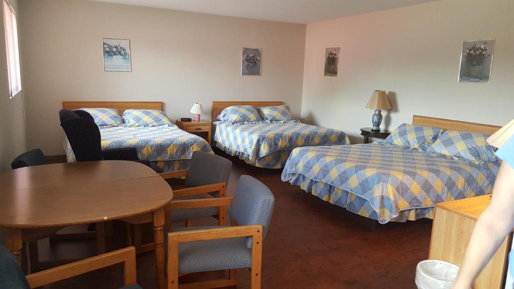 a room with two beds and a table and a table and chairs at Alpine Motel in heart of Wisconsin Dells downtown. in Wisconsin Dells