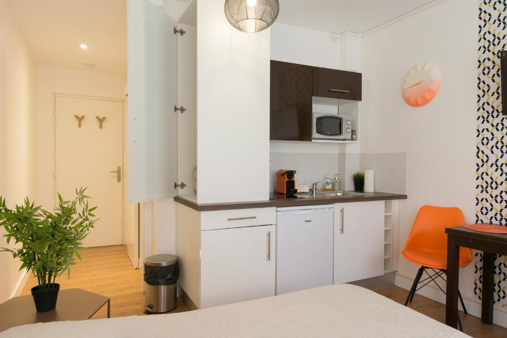 eine kleine Küche mit weißen Schränken und einer Mikrowelle in der Unterkunft Studio Sympa Ramblas Centre Toulouse in Toulouse