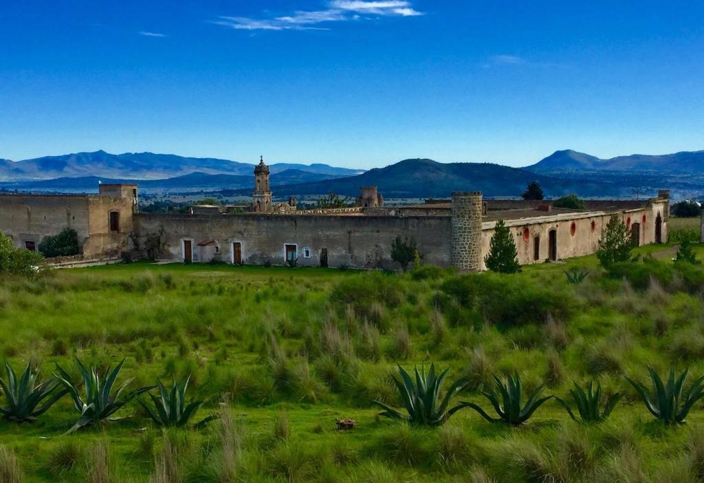 um edifício antigo num campo com montanhas ao fundo em Hacienda Santa Barbara Casa Malinche em Huamantla