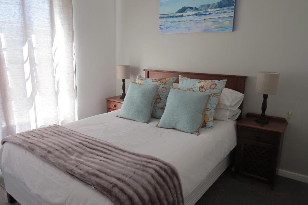 a bedroom with a white bed with blue pillows at Chamomile Cottage in Muizenberg