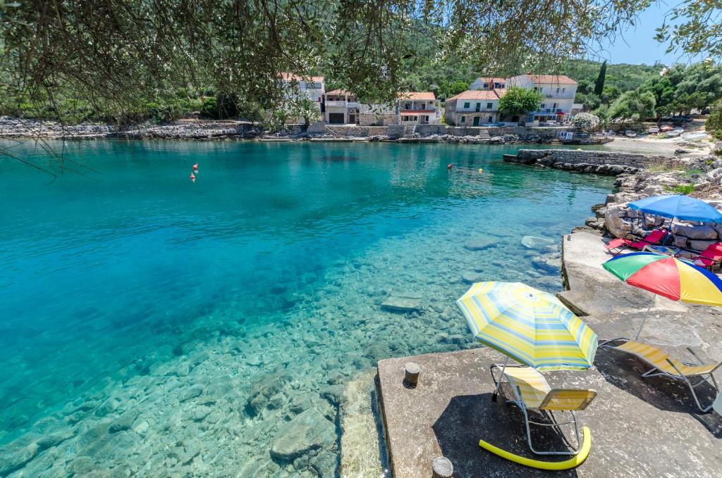 a river with umbrellas and chairs in the water at Apartments Dinko in Gdinj