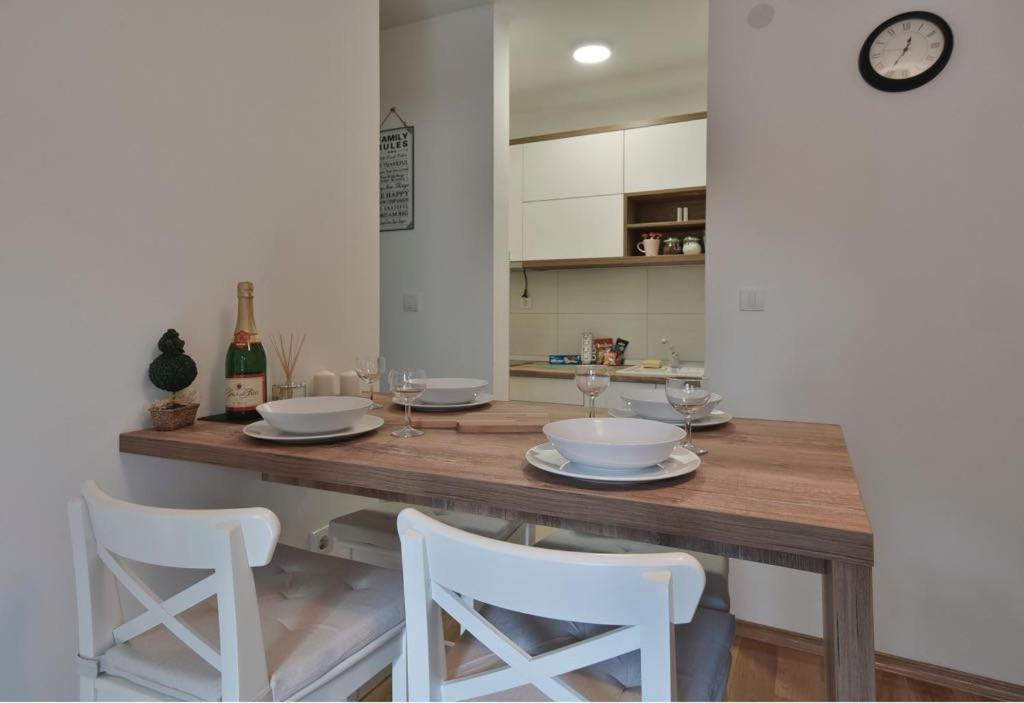 a kitchen with a wooden table and white chairs at Lux Apartman Daria in Zlatibor