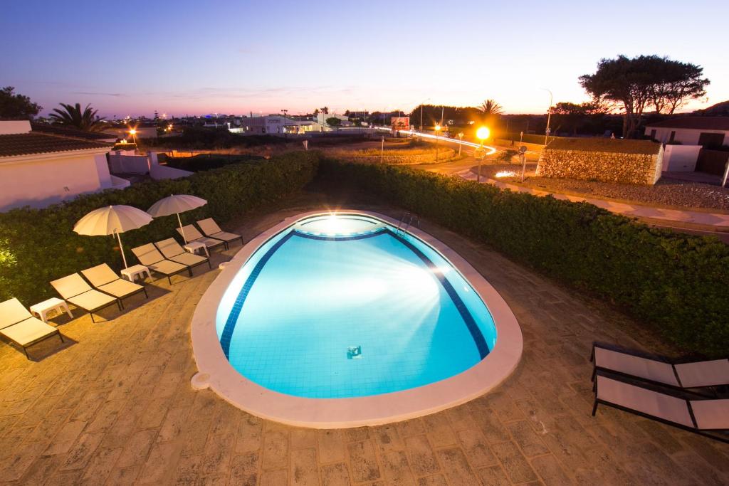 an overhead view of a swimming pool with chairs and umbrellas at Nuvolet Apartaments in Cala en Blanes