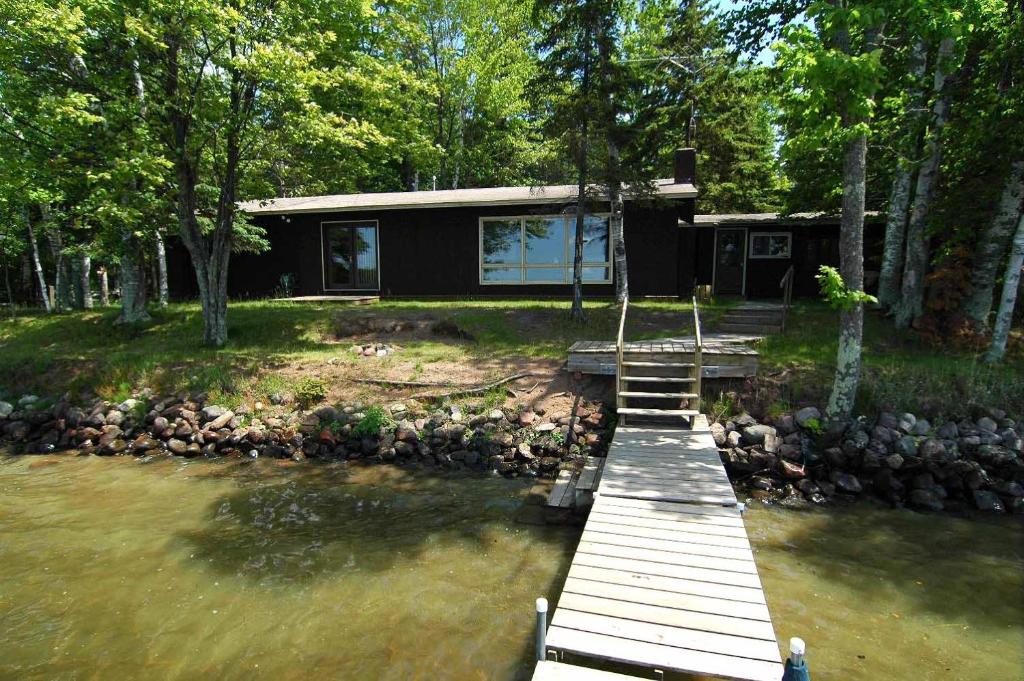 ein Haus mit einem Holzsteg im Wasser in der Unterkunft Ranch-Style Seidls Home in Namekagon