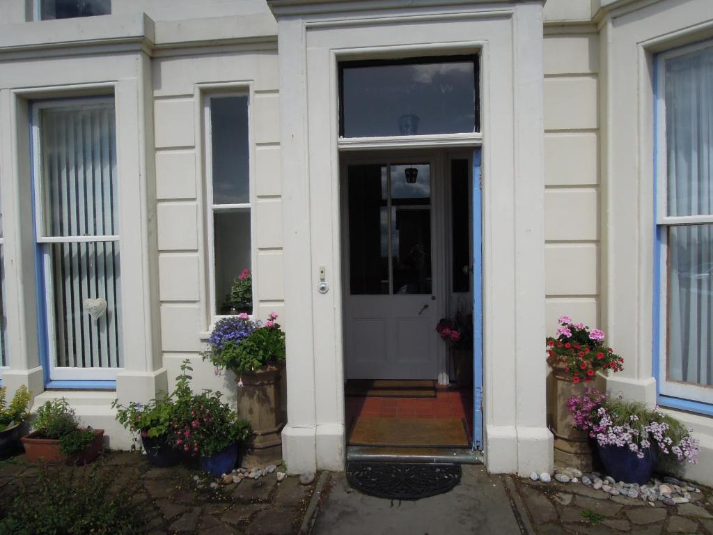 a white front door of a house with potted plants at Seascape Largo in Lundin Links