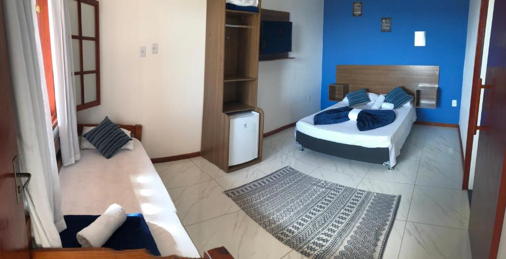 een slaapkamer met een bed en een bank in een kamer bij Canto da Praia Suítes in Arraial do Cabo