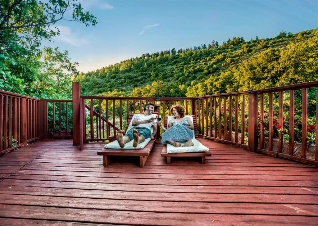 a man and woman sitting on their beds on a deck at Spa in The Woods - B&B in Amirim in Amirim