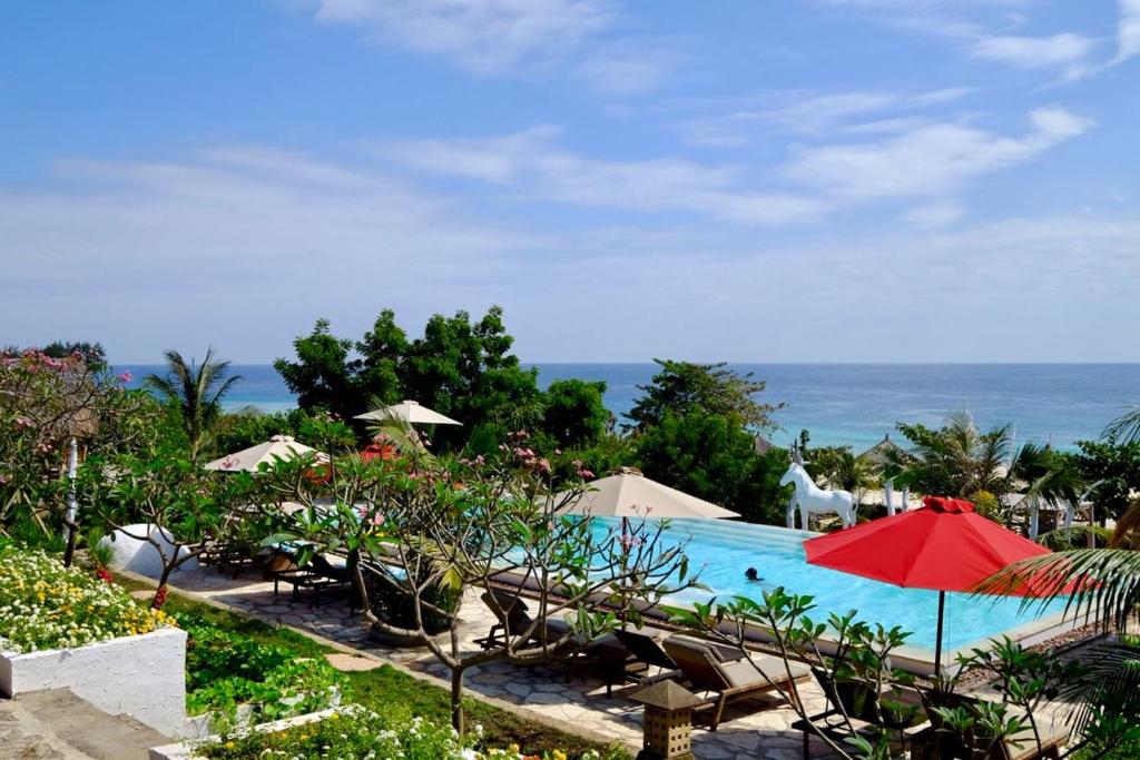 a swimming pool with chairs and a red umbrella at Mario Hotel and Cafe in Weetebula