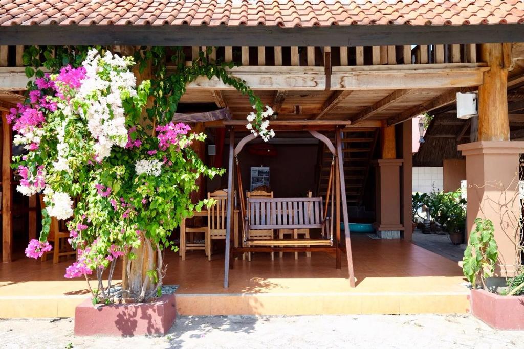 a porch with a swinging bench and flowers at Mario Hotel and Cafe in Weetebula