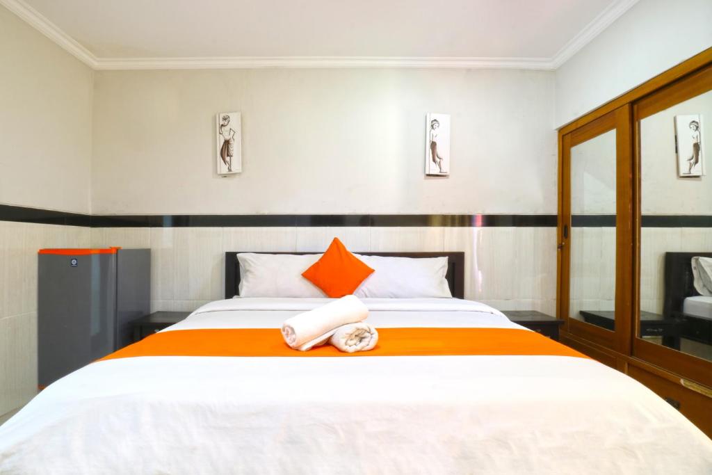 a bedroom with a large bed with orange and white sheets at Rena Segara House Kuta in Kuta