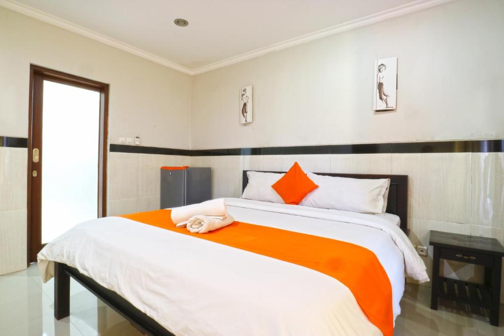 a bedroom with a large bed with an orange and white blanket at Rena Segara House Kuta in Kuta
