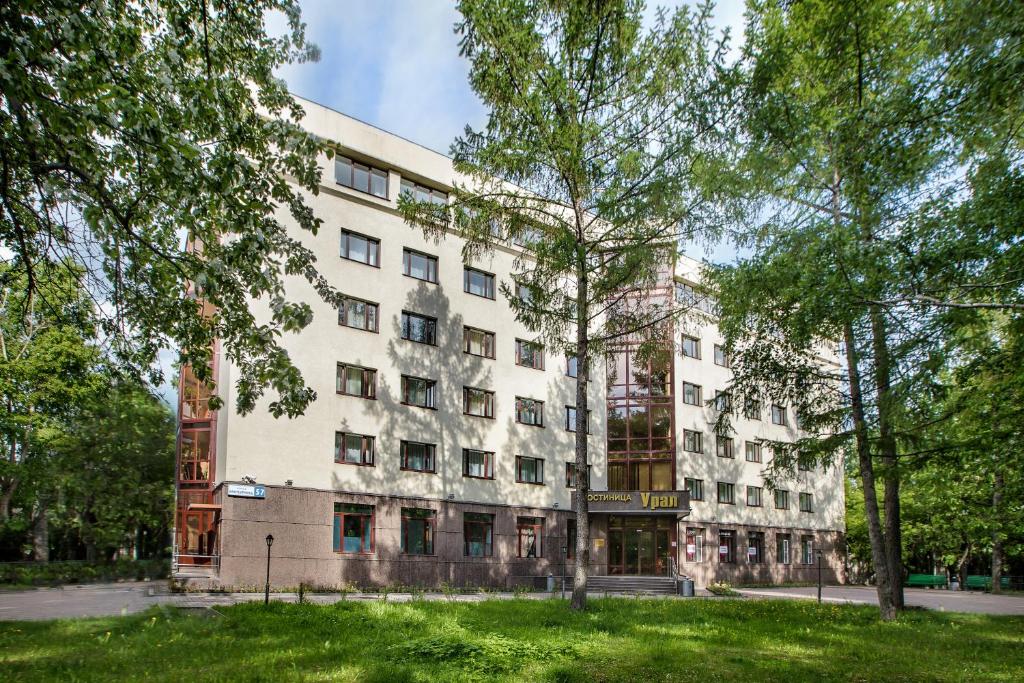 um grande edifício branco com árvores em frente em Ural Hotel em Yekaterinburg