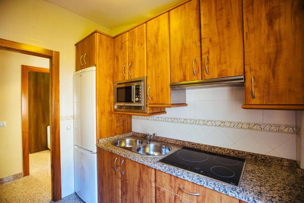 シウダード・ロドリゴにあるApartamentos Arcosのキッチン(木製キャビネット、シンク、電子レンジ付)