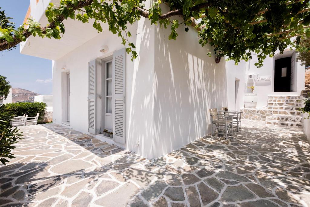a white house with white walls and a patio at Vounali Rooms in Naousa