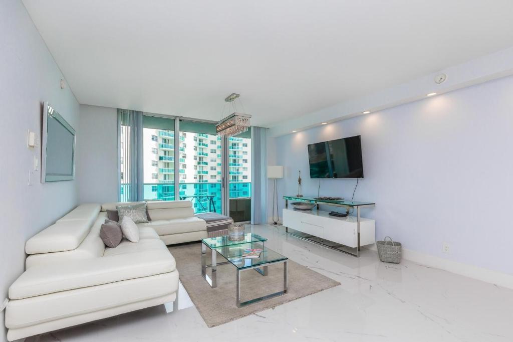 ein Wohnzimmer mit einem weißen Sofa und einem Glastisch in der Unterkunft Two bed beach condo at Sian Miami in Hollywood