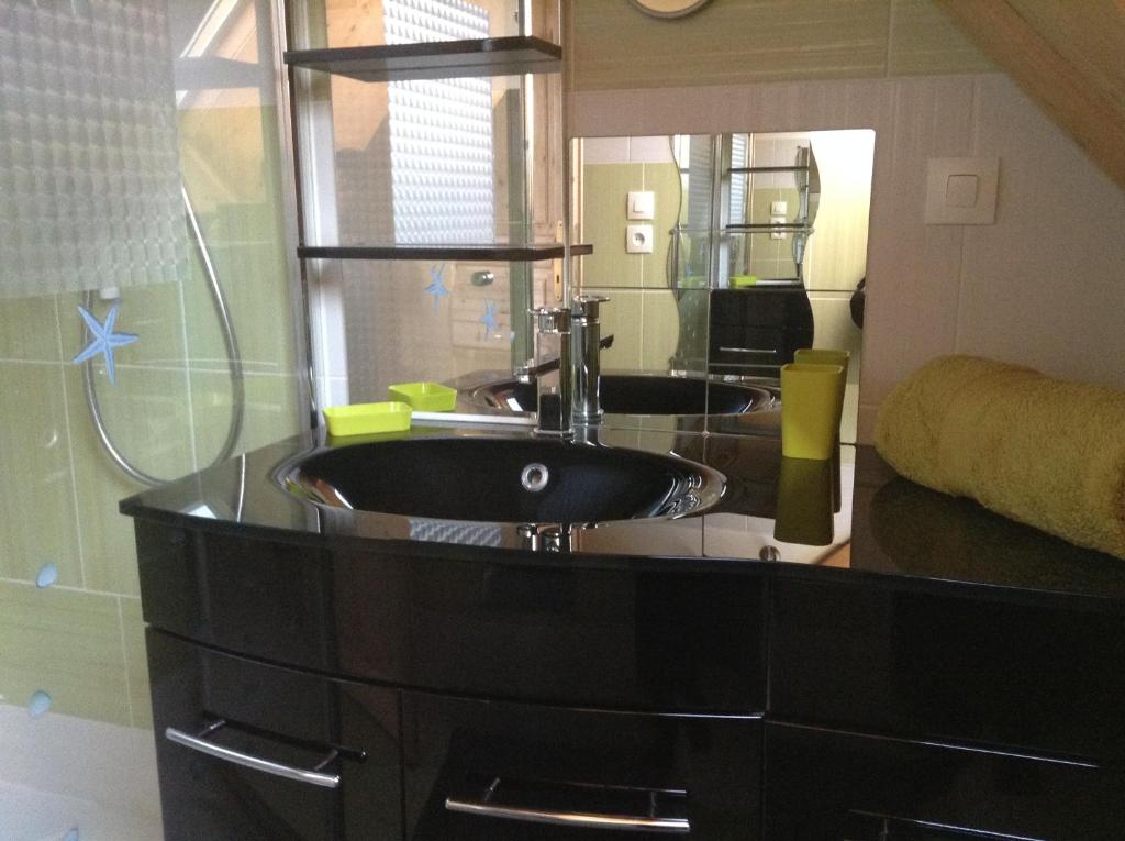 a bathroom with a black sink and a mirror at Chez MARLENE in Quettehou