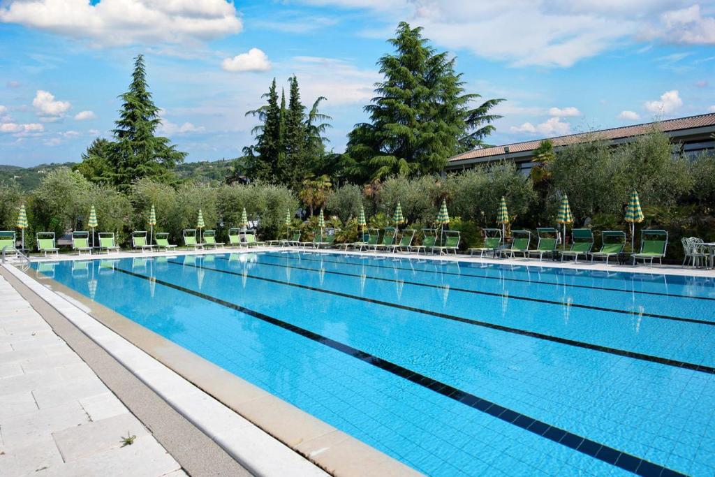 einen großen Pool mit Stühlen und Bäumen in der Unterkunft Park Hotel Oasi in Garda