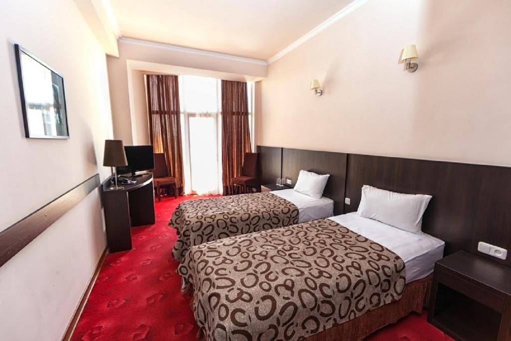 pokój hotelowy z 2 łóżkami i czerwonym dywanem w obiekcie Regineh Hotel w Erywaniu