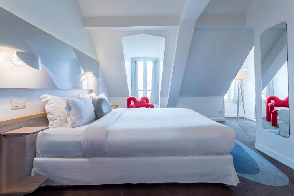 a bedroom with a white bed and red chairs at Hôtel Le Marcel Paris Gare de l'Est in Paris