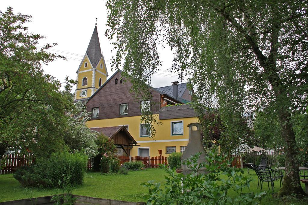 ein gelbes Gebäude mit einer Kirche mit einem Kirchturm in der Unterkunft Appartements am Kurpark in Bad Mitterndorf