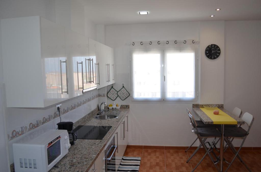 een witte keuken met een wastafel en een raam bij VV Sarmiento in Vecindario