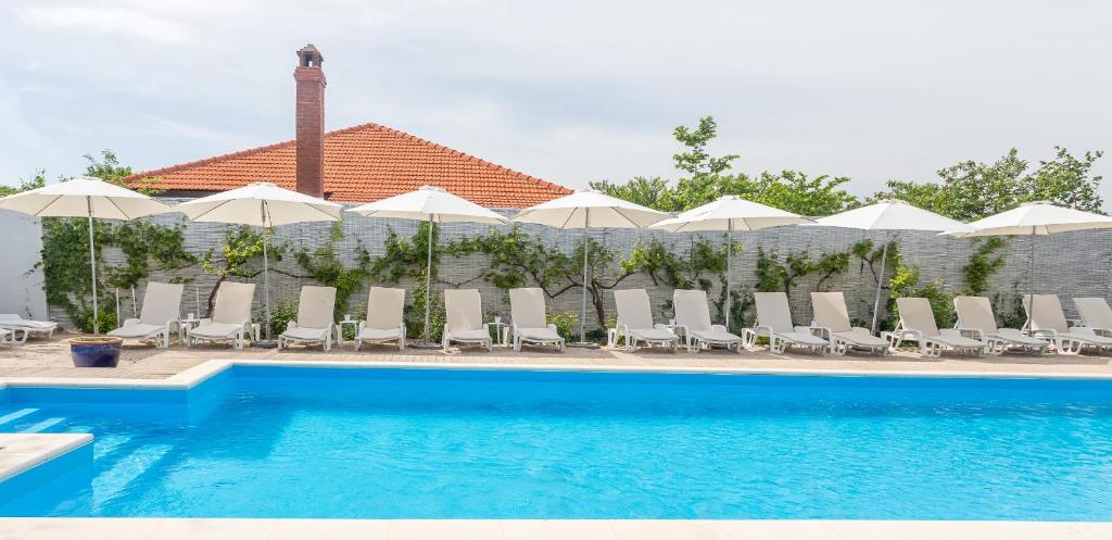 a swimming pool with chairs and umbrellas at Casa Stavros in 2 Mai