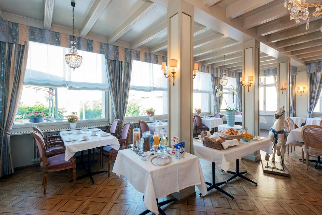 een eetkamer met tafels, stoelen en ramen bij Hôtel du Cheval-Blanc in Saint-Blaise