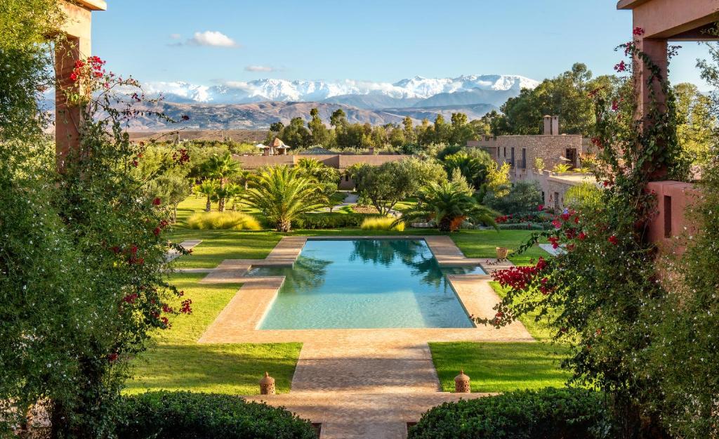 una piscina en un patio con montañas al fondo en The Capaldi Hotel, Restaurant & Spa, en Lalla Takerkoust