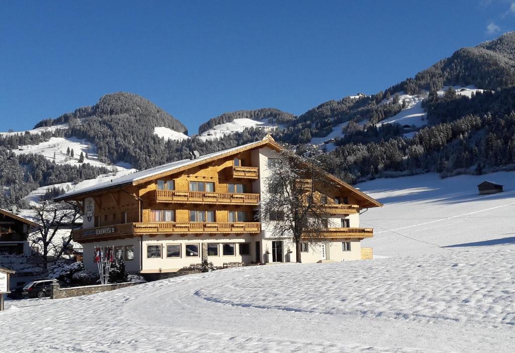 a building in the snow with mountains in the background at Hotel Edelweiss in Itter