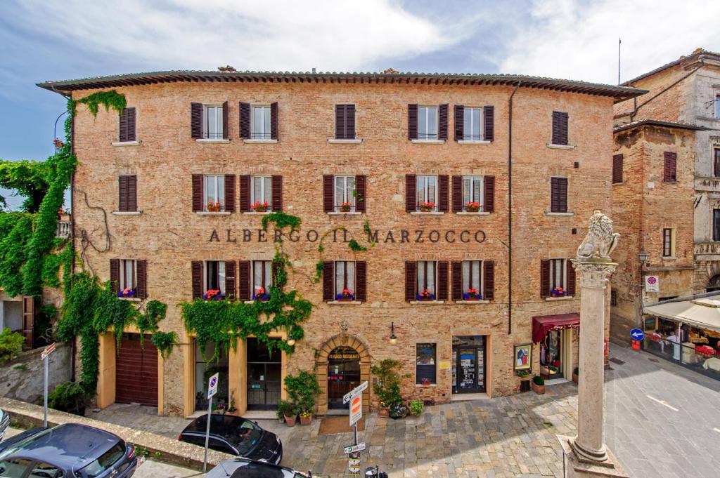 un gran edificio de ladrillo con un cartel. en Albergo Il Marzocco, en Montepulciano