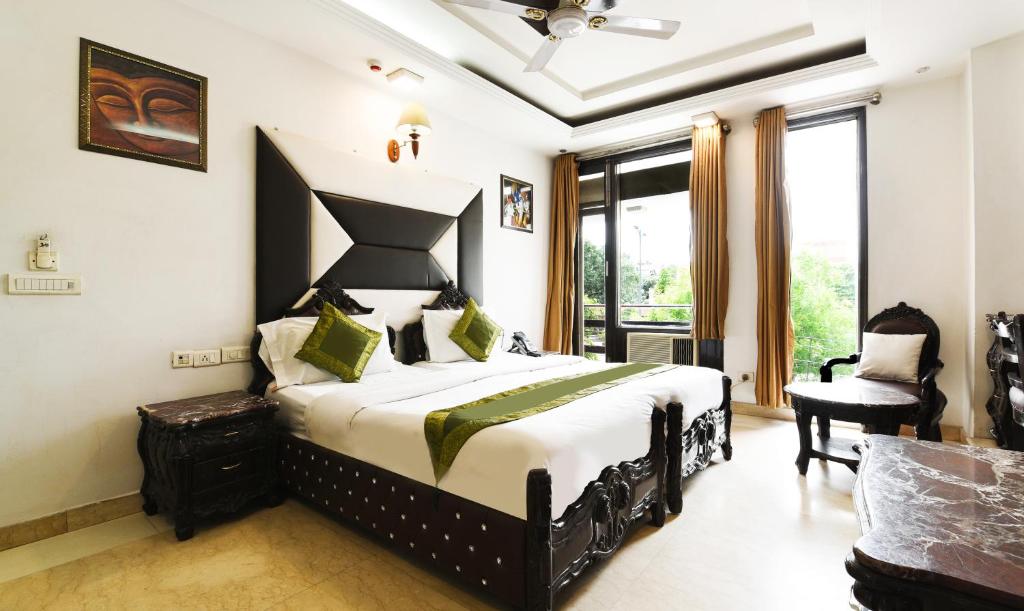 Schlafzimmer mit einem Kingsize-Bett und einem Stuhl in der Unterkunft Hotel Baljeet Lodge in Neu-Delhi