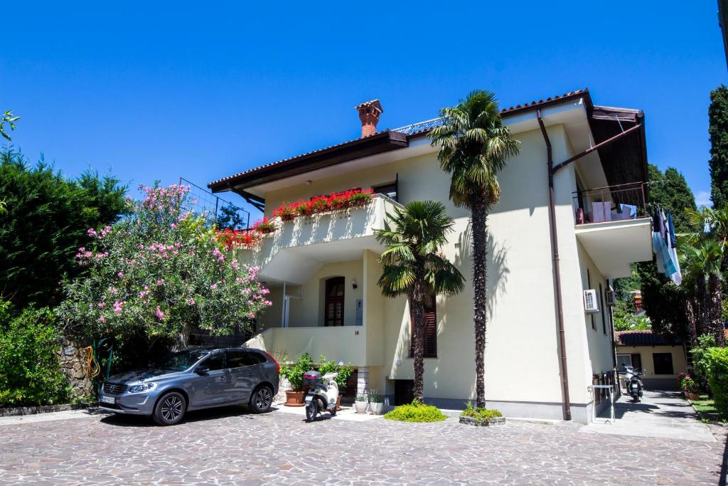 a car parked in front of a white house at Apartments Bukovšek in Portorož