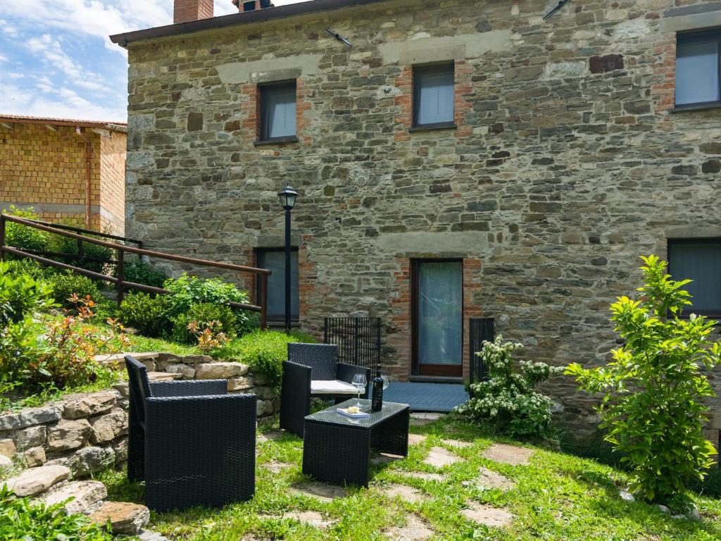 a stone house with chairs and a table in front of it at Pretty Farmhouse with pool in Sestino