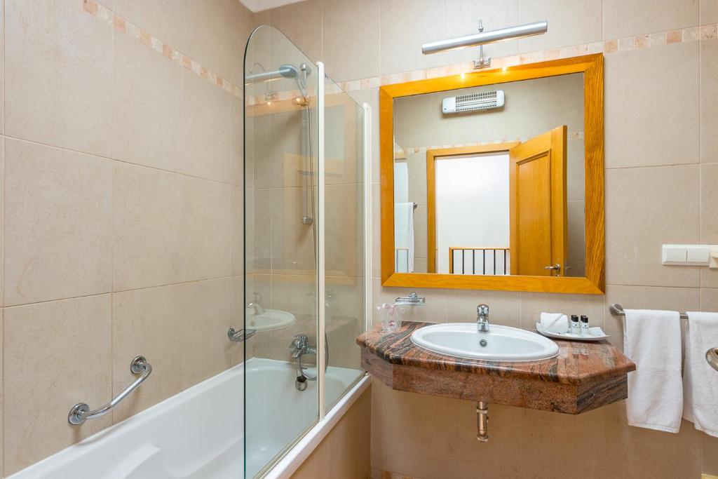 a bathroom with a sink and a shower and a mirror at Pestana Palm Gardens in Carvoeiro