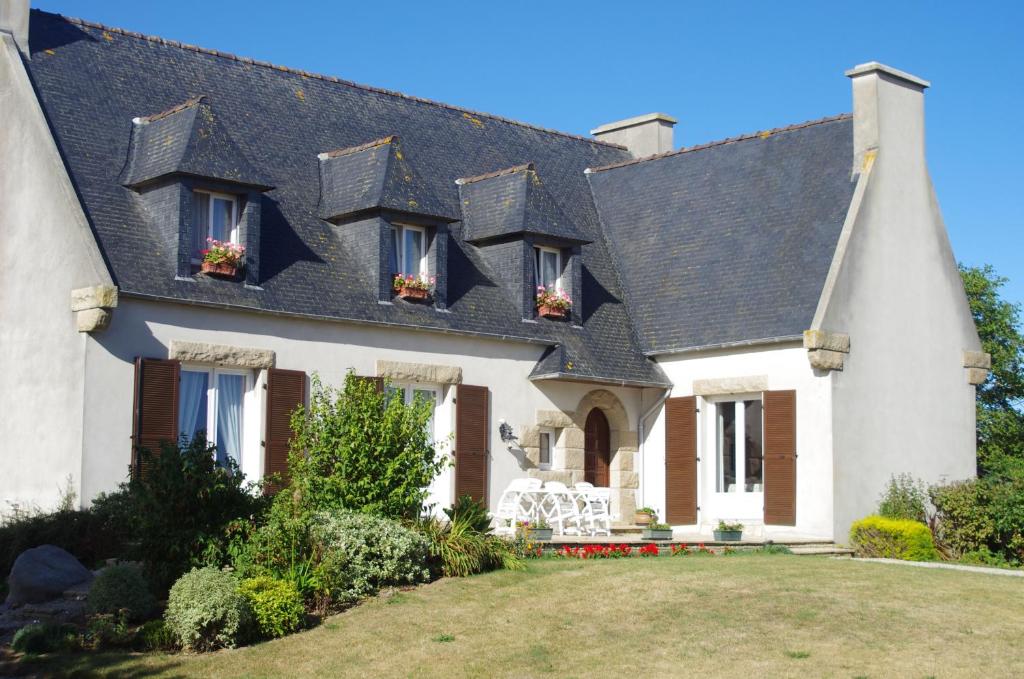 a white house with a black roof at Chambres d'hôtes du Theven in Plougoulm