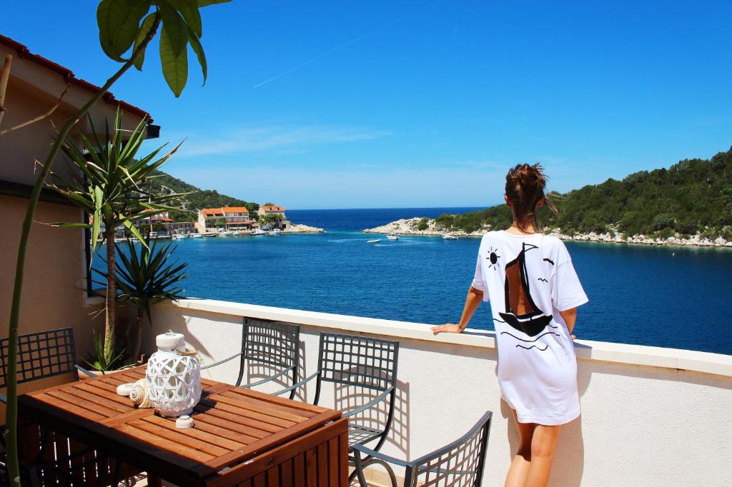 a woman standing on a balcony looking at the ocean at Accommodation Triton in Lastovo