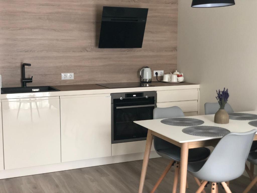 a kitchen with white cabinets and a table and a sink at Memel home old city apartment in Klaipėda