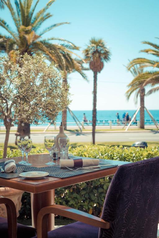 a table with wine glasses and a table with palm trees at Westminster Hotel & Spa Nice in Nice