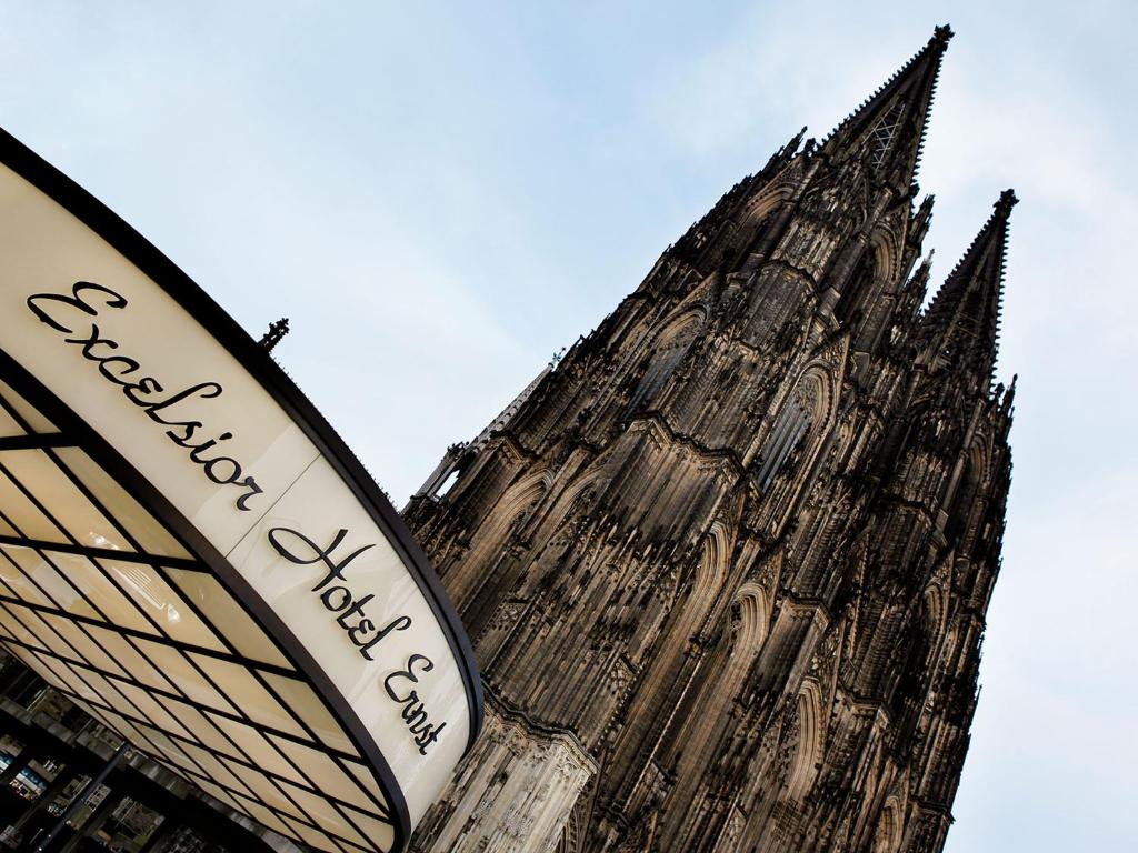 un edificio alto con una torre de reloj en Excelsior Hotel Ernst am Dom, en Colonia