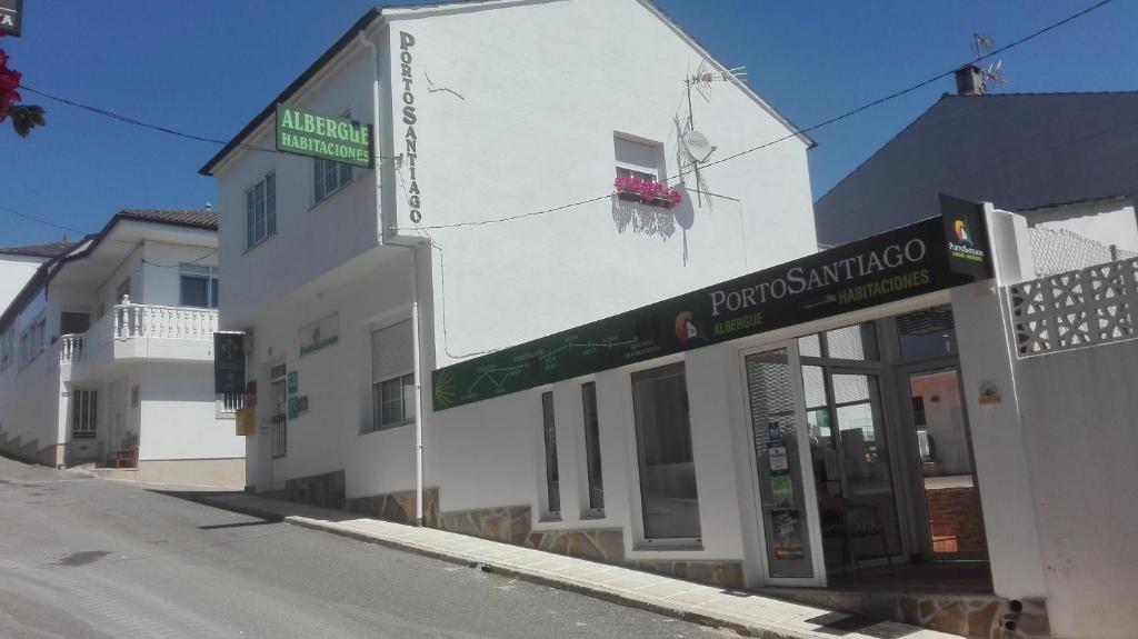 un edificio blanco con un letrero verde. en PortoSantiago, en Portomarín