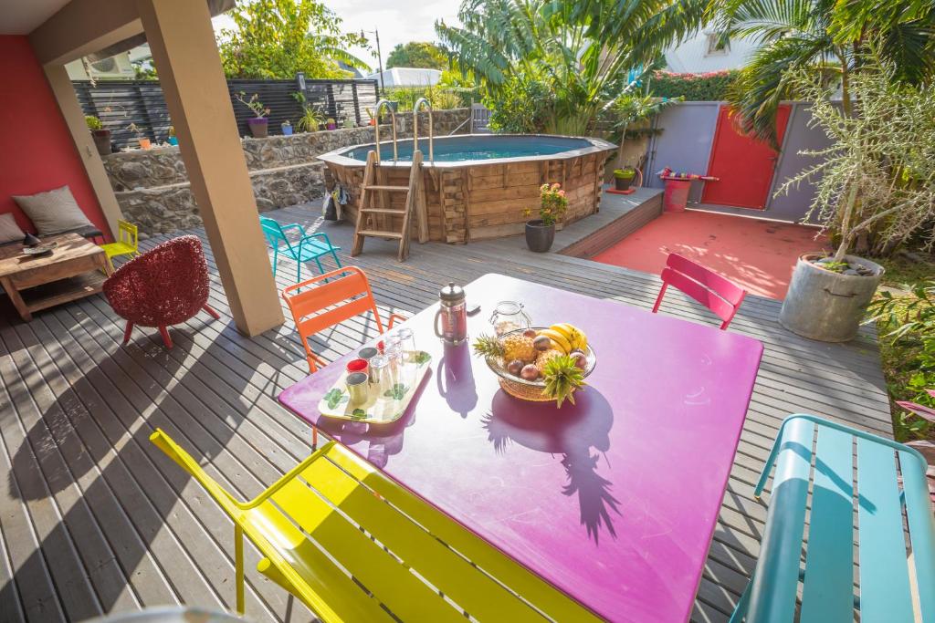 einen Tisch und Stühle mit einer Obstschale und einem Pool in der Unterkunft Villa Yapaplupres in Saint-Leu